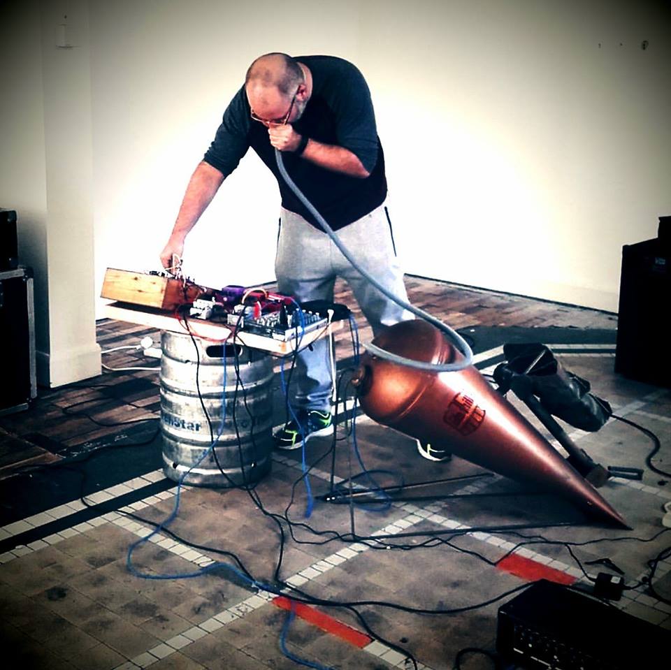a Photo showing artist Zero Gradient performing with his musical instrument made from an old copper boiler